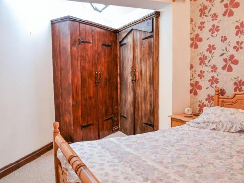 a bedroom with a wooden wardrobe and a bed at The Old Brewery in Builth Wells