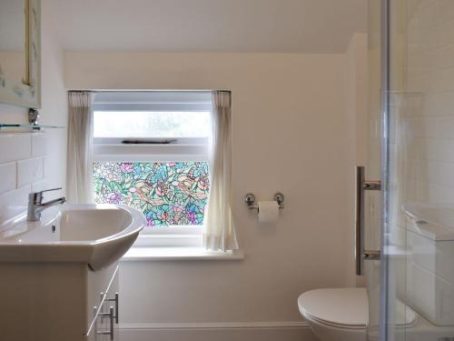 a bathroom with a sink and a toilet and a window at Beech Cottage in Whitwell