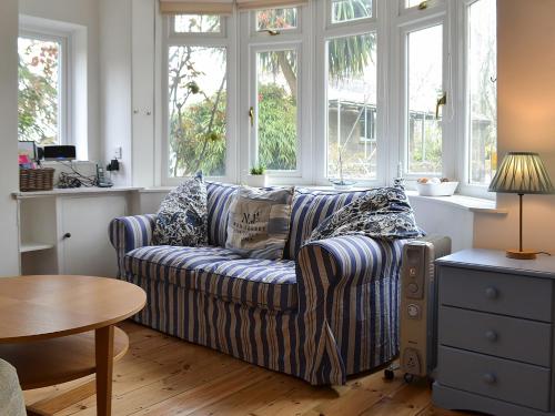 ein Wohnzimmer mit gestreifter Couch und Fenstern in der Unterkunft Beech Cottage in Whitwell