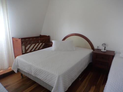 a bedroom with a white bed and a wooden floor at ROSA CORTIANA Escalera in São Gabriel