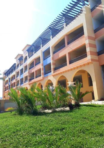 a large building with palm trees in front of it at Marina city port ghalib chalet in Port Ghalib
