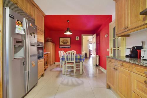 a kitchen with red walls and a table with chairs at Chalet Navacerrada Piscina Privada in Navacerrada