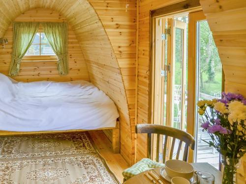 1 dormitorio en una cabaña de madera con 1 cama y 1 mesa en The Squirrels strelley Barn, en Woodham Mortimer