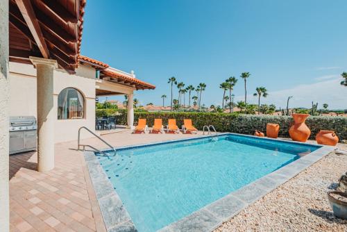 a swimming pool with chairs and a house at Tierra Del Sol Resort & Golf in Palm-Eagle Beach
