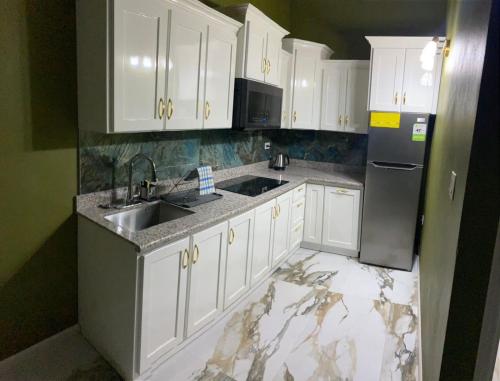 a white kitchen with a sink and a refrigerator at paradise cove in Spanish Town