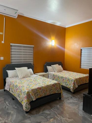 two beds in a room with orange walls at paradise cove in Spanish Town