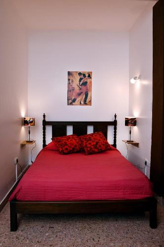 1 dormitorio con 1 cama roja y 2 lámparas en SOÑAR CON FLORES Y TANGOS en Buenos Aires