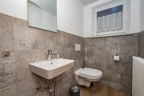 a bathroom with a sink and a toilet and a window at Ferienwohnung Kircher in Obermaiselstein