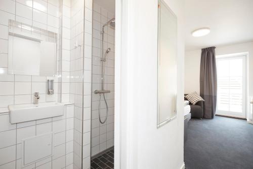 a white bathroom with a sink and a shower at Hotel Osted in Lejre