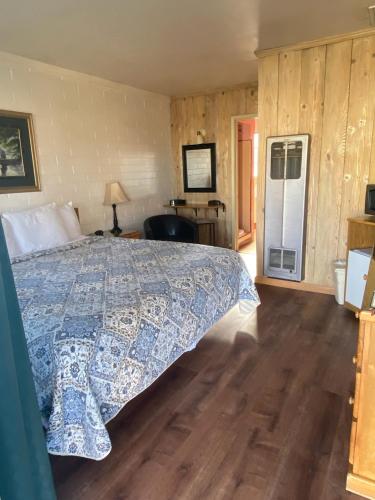 a bedroom with a bed with a blue and white bedspread at Bishop Village Motel in Bishop