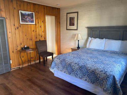 um quarto com uma cama, uma cadeira e uma mesa em Bishop Village Motel em Bishop