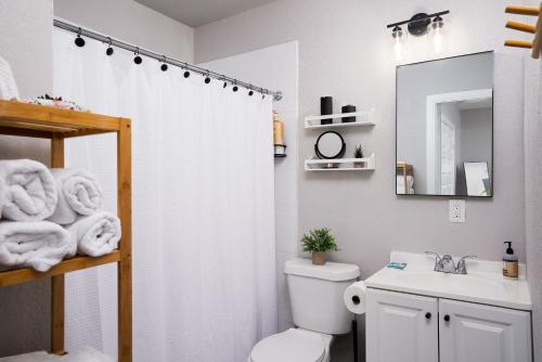 La salle de bains est pourvue d'un rideau de douche blanc et de toilettes. dans l'établissement Modern 3 Bed, 2 Bath Home Minutes to Downtown & Alamodome, à San Antonio
