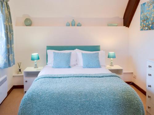 a bedroom with a blue bed with two tables and two lamps at Discovery in Cheriton Bishop