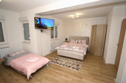 a bedroom with two beds and a flat screen tv at Apartman Mladen in Trebinje
