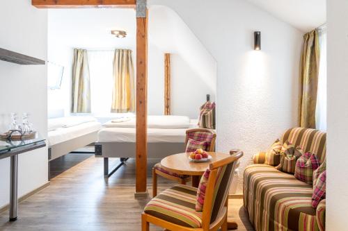 a hotel room with two beds and a table and chairs at Hotel Restaurant Krehl's Linde in Stuttgart