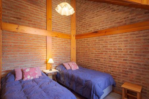 two beds in a room with a brick wall at Cabañas Del Lacar in San Martín de los Andes