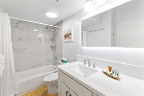 a white bathroom with a sink and a tub and a toilet at Upscale Penthouse with Ocean Views & Free Parking! in Honolulu
