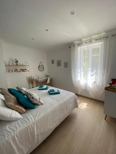 um quarto com uma grande cama branca com almofadas azuis em Chambre d'hôtes Zephyr Libeccio Le Moulin de Prédelles em Reillanne