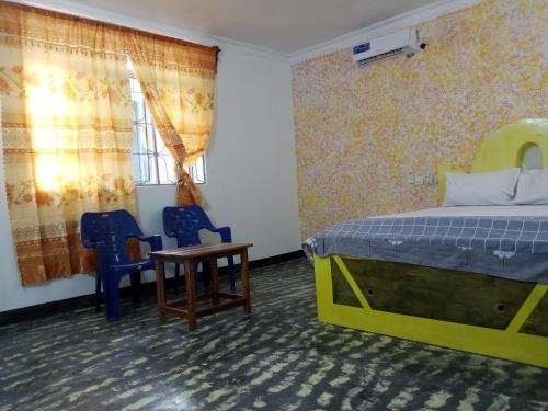 a bedroom with a bed and two chairs and a table at Ndiro Beach House Kendwa in Kendwa