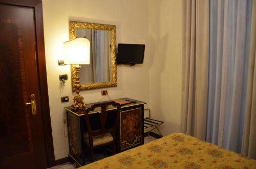 a bedroom with a bed and a mirror and a lamp at Hotel Des Epoques in Rome