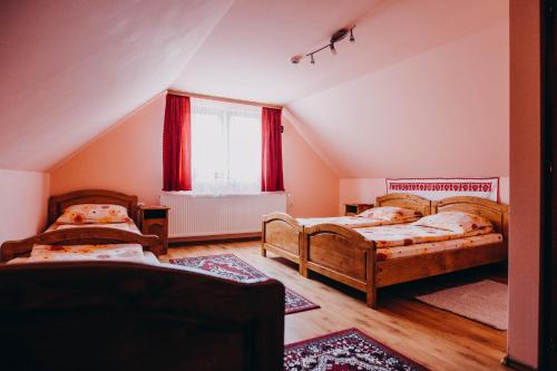 - une chambre mansardée avec 2 lits et une fenêtre dans l'établissement Casa Roland, à Gheorgheni