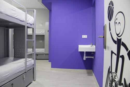 a room with purple walls and a sink and bunk beds at BcnSportHostels in Barcelona