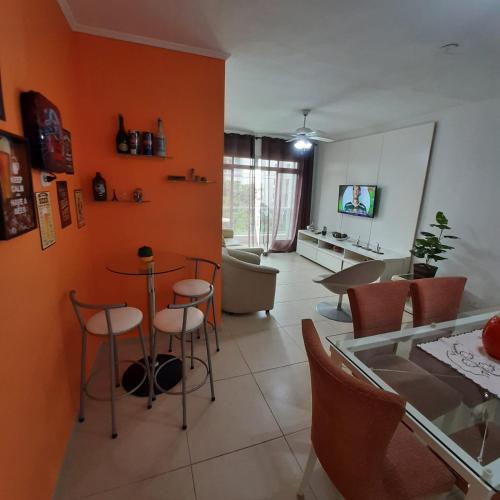 un soggiorno con pareti arancioni, tavolo e sedie di Apartamento próximo a praia - Enseada Guarujá a Guarujá