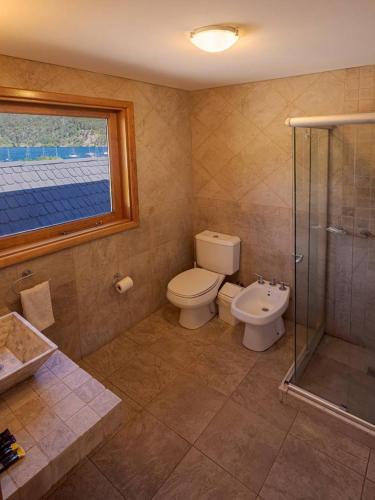a bathroom with a toilet and a glass shower at Cabañas Del Lacar in San Martín de los Andes