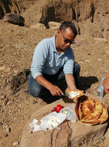 a man sitting on a rock eating a pie at Gite Kasbah La Palmeraie in Skoura