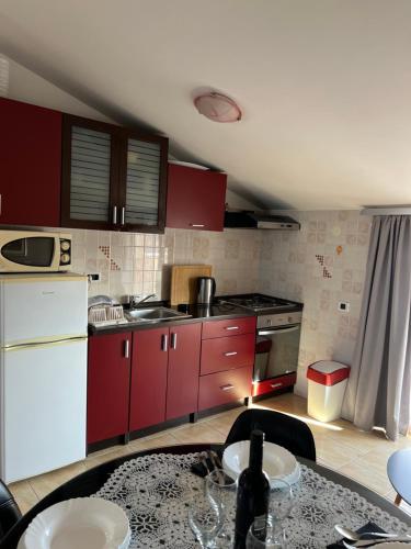 a kitchen with red cabinets and a white refrigerator at Apartmani M&L in Medulin