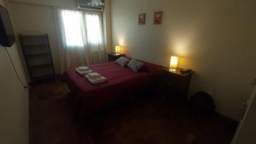 1 dormitorio con 1 cama roja con 2 almohadas y ventana en Altos Mendoza Av Gutiérrez Cochera Gratis! en Mendoza