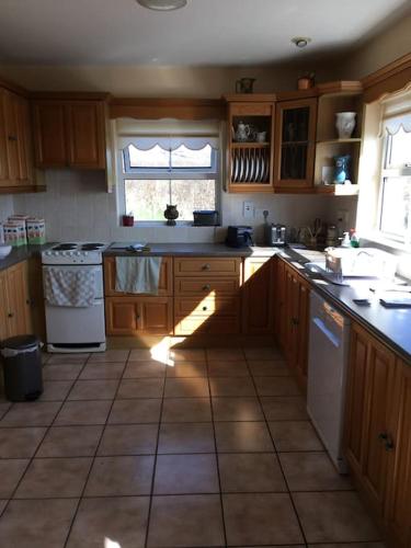 a kitchen with wooden cabinets and a tile floor at Bungalow by the sea in Gortgarriff