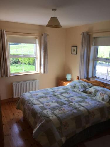 a bedroom with a bed and two windows at Bungalow by the sea in Gortgarriff