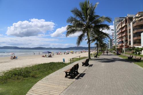 una playa con una palmera y gente sentada en bancos en ACHOU! O melhor custo-benefício de Itapema!, en Itapema