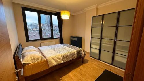 1 dormitorio con cama y ventana grande en Прекрасная двухуровневая квартира с террасой, en Estambul