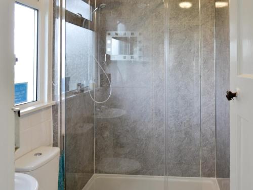a bathroom with a shower with a glass door at Searchlight Cottage in Fraisthorpe
