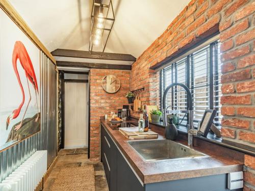 uma cozinha com um lavatório e uma parede de tijolos em The Twisted Toad em Guisborough