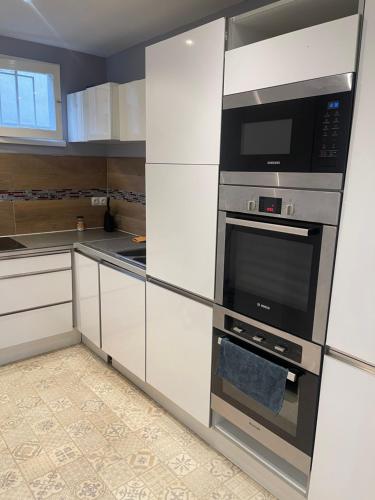 une cuisine avec des armoires blanches et des appareils en acier inoxydable dans l'établissement Appartement à 2 pas de la gare, à Chalon-sur-Saône