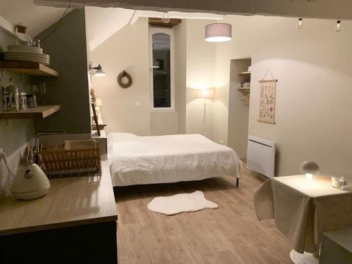ein Schlafzimmer mit einem weißen Bett und einem Tisch in der Unterkunft Studio du Grand Beaumont in Saint-Mélaine-sur-Aubance