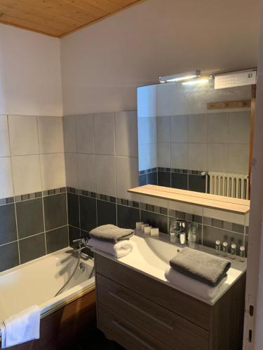 une salle de bain avec une baignoire, un lavabo et un miroir dans l'établissement Hotel Le Concorde, à Morzine