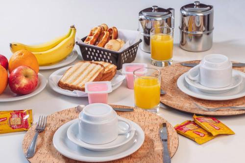 a table with plates of breakfast food and fruit at Frenesi Motel Rondon in Marechal Cândido Rondon