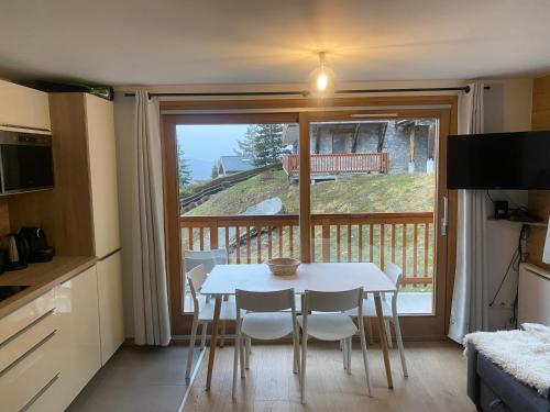 Il dispose d'un balcon et d'une cuisine avec une table et des chaises. dans l'établissement Méribel 2 pièces avec cabine, centre, proche commerce et pistes avec parking et wifi état neuf, à Les Allues