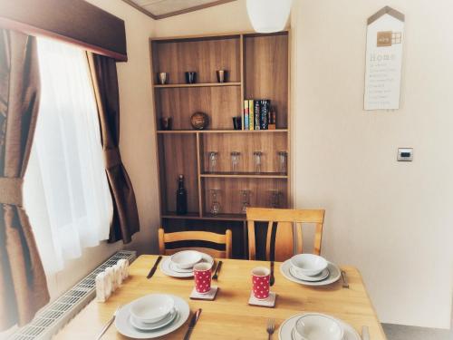 - une table à manger avec des assiettes et des tasses dans l'établissement 31 solent village, à Porchfield