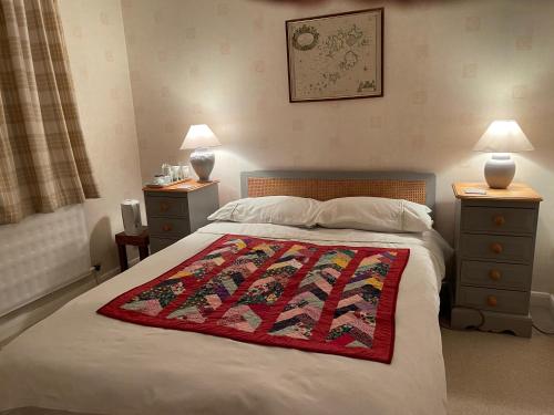 a bedroom with a bed with a red blanket on it at Silver Lodge Guest House in Mildenhall