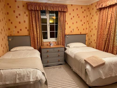 a bedroom with two beds and a window at Silver Lodge in Mildenhall
