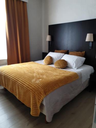 a bedroom with a large bed with a yellow blanket at Hotel Gulden Vlies in Bruges