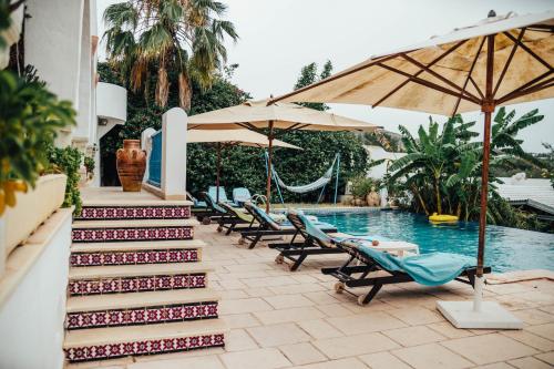a pool with chairs and umbrellas next to a swimming pool at DAR BELDI in Hammamet