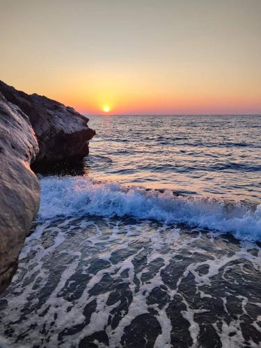 a sunset over the ocean with a rocky beach at Sun Camero Apartments in Pomos