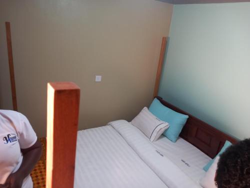 uma cama num pequeno quarto com uma pessoa ao lado em Habermotel Enterprise Ltd em Entebbe