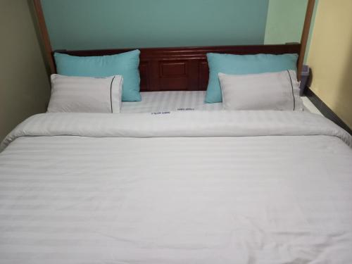 a bed with white sheets and blue pillows at Habermotel Enterprise Ltd in Entebbe